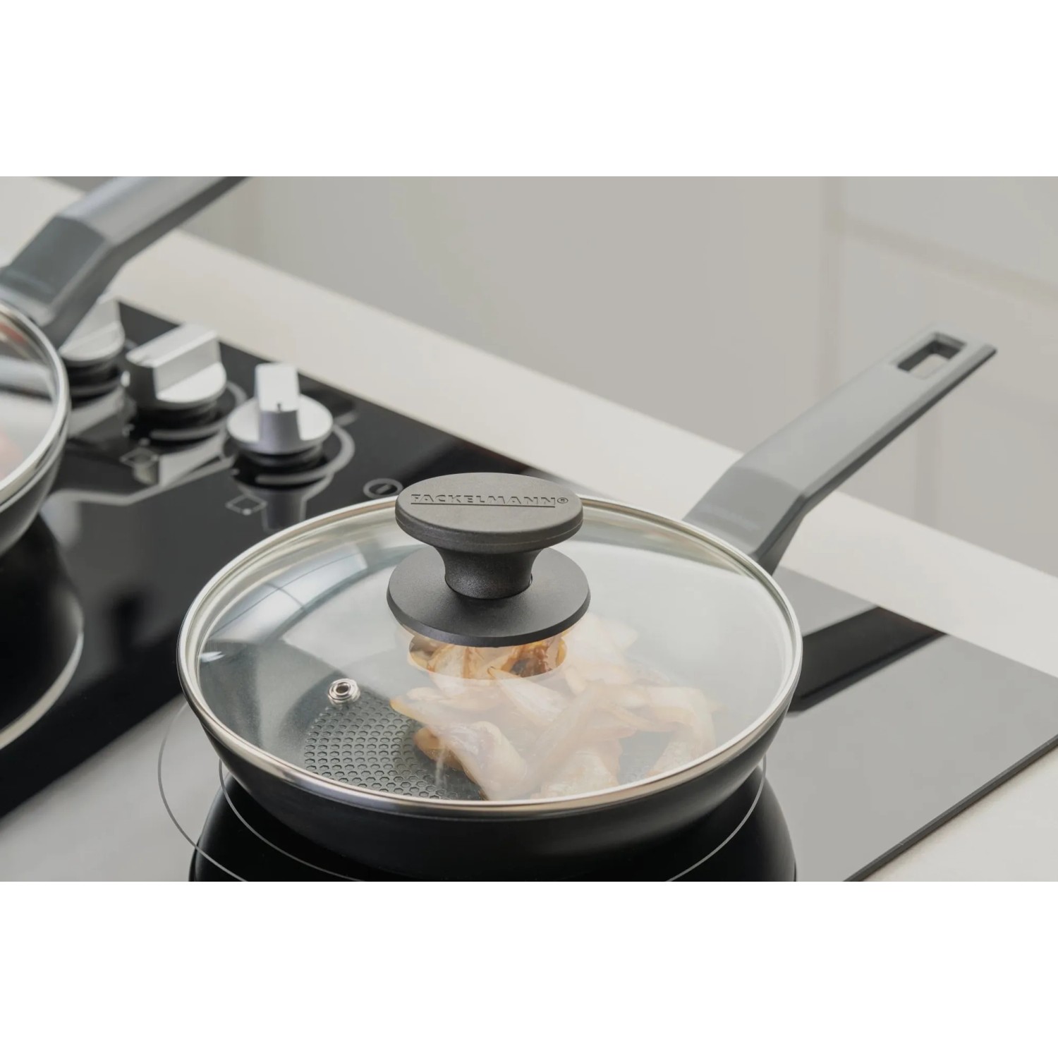 Fackelmann Pfannenglasdeckel, 20 cm, auf einer Pfanne mit Speisen auf einem Herd.
