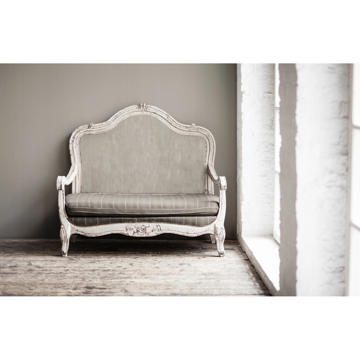 Beige-braune Vliestapete Uni (FSC®) an Wand hinter antikem Sofa.