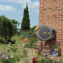 Hozelock Auto Reel Schlauchtrommel mit 30m Schlauch an einer Backsteinmauer im Garten.