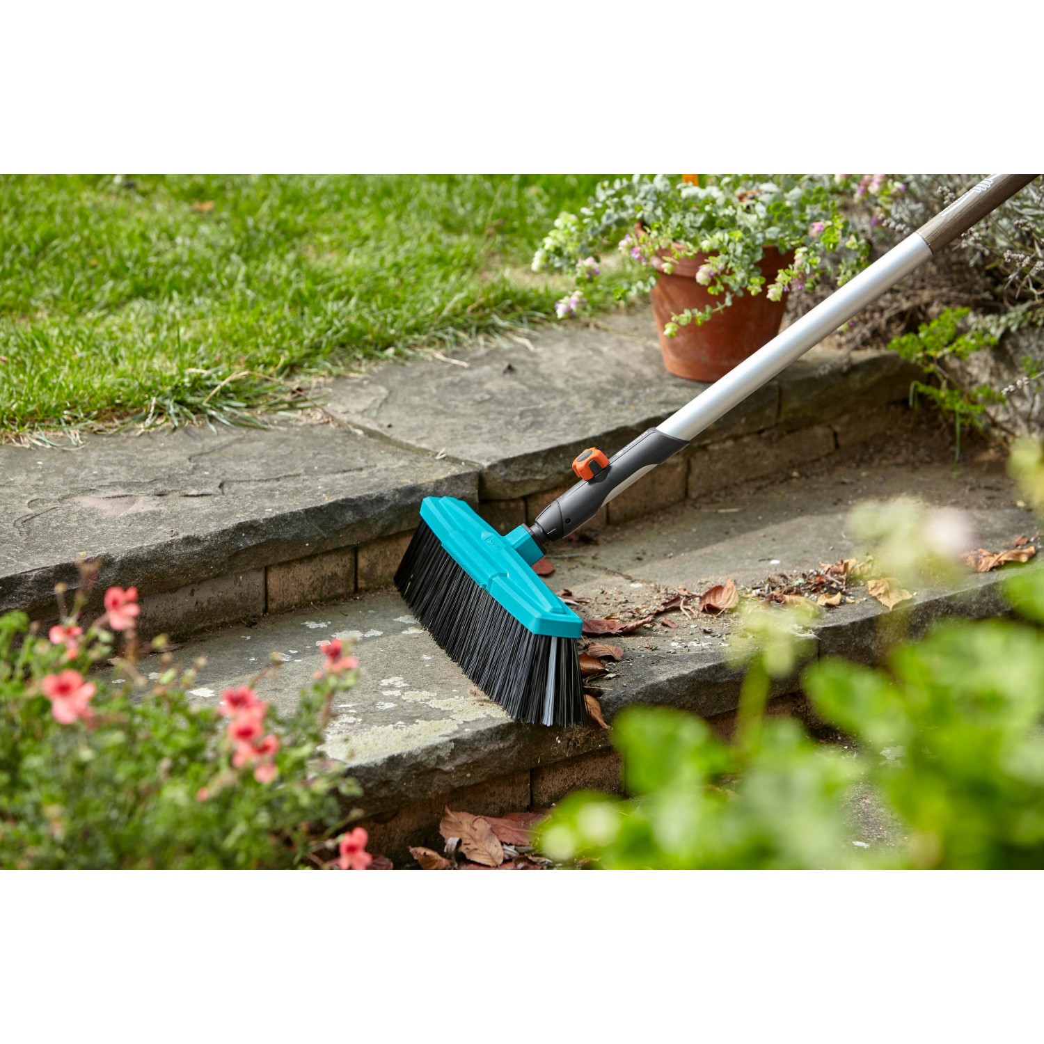 Gardena Combisystem Set mit Straßenbesen, Fugenbürste und Stiel im Einsatz auf Steinstufen.