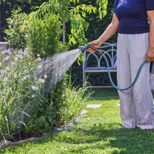 Frau gießt Garten mit Gardena Bewässerungsbrause Classic. Gartenspritze mit weichem Sprühbild.
