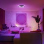 Schwarze Philips Hue Infuse L Deckenleuchte mit farbiger Beleuchtung in Wohnzimmer-Szene.