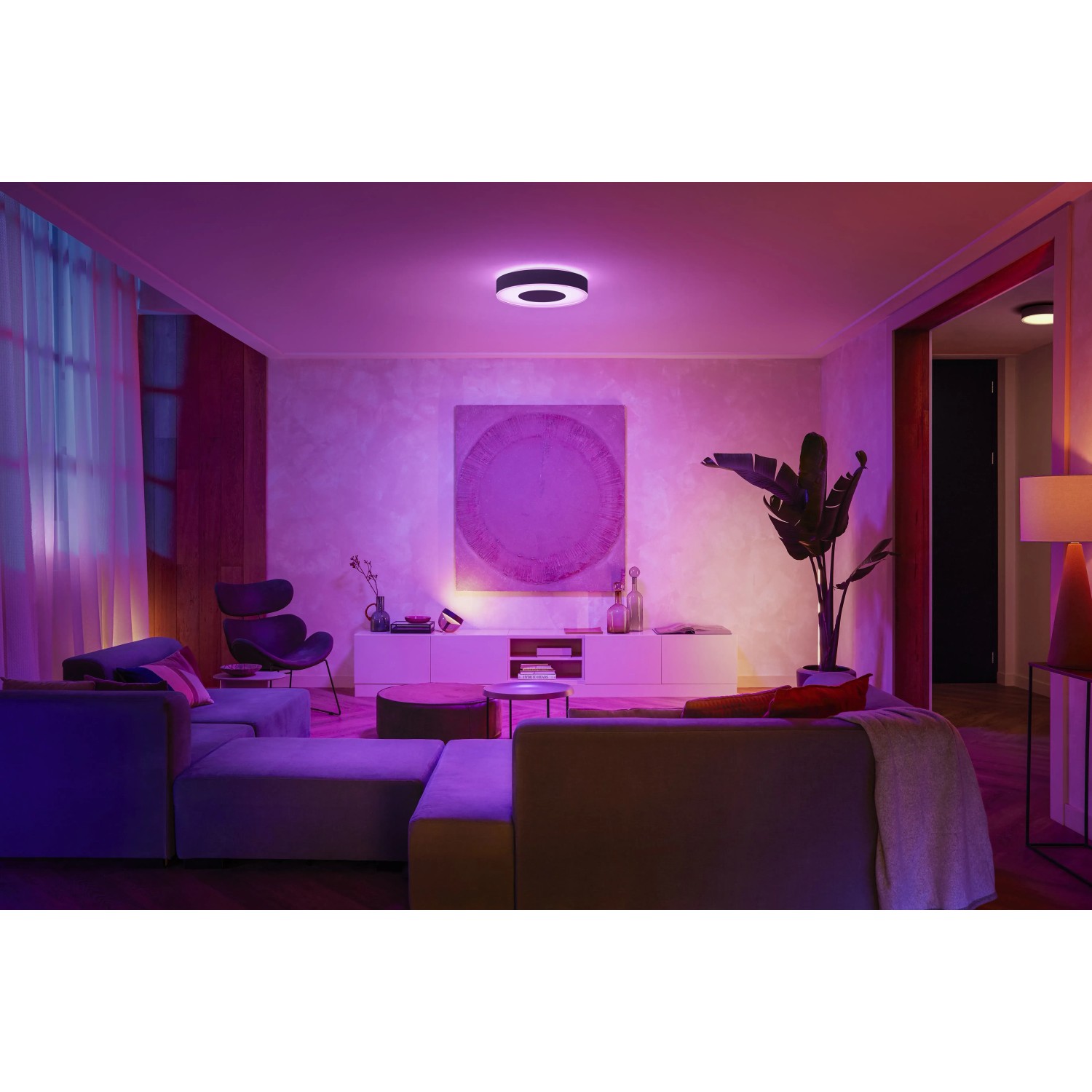 Schwarze Philips Hue Infuse L Deckenleuchte mit farbiger Beleuchtung in Wohnzimmer-Szene.