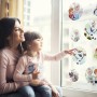 Mutter und Kind betrachten Fenstersticker Frozen Springday an einem Fenster.