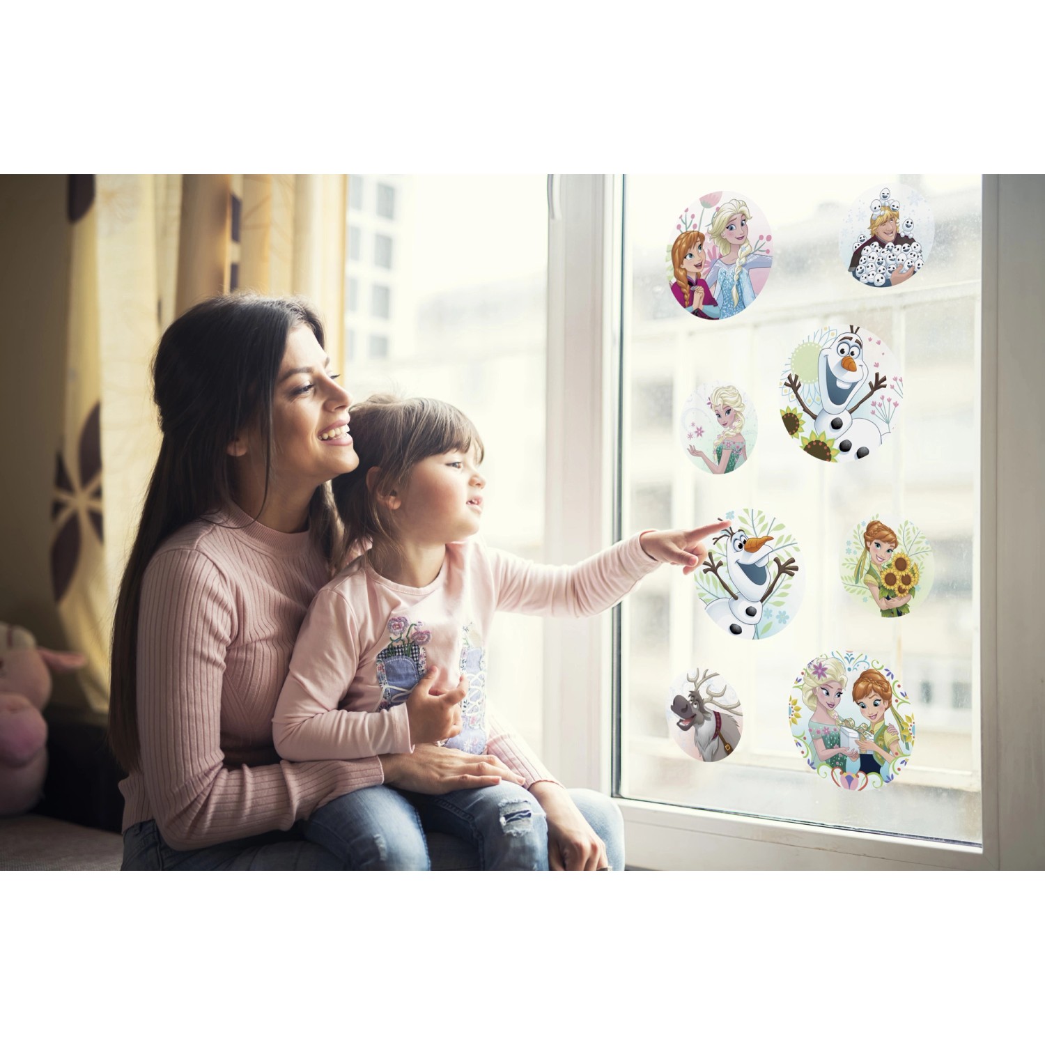 Mutter und Kind betrachten Fenstersticker Frozen Springday an einem Fenster.