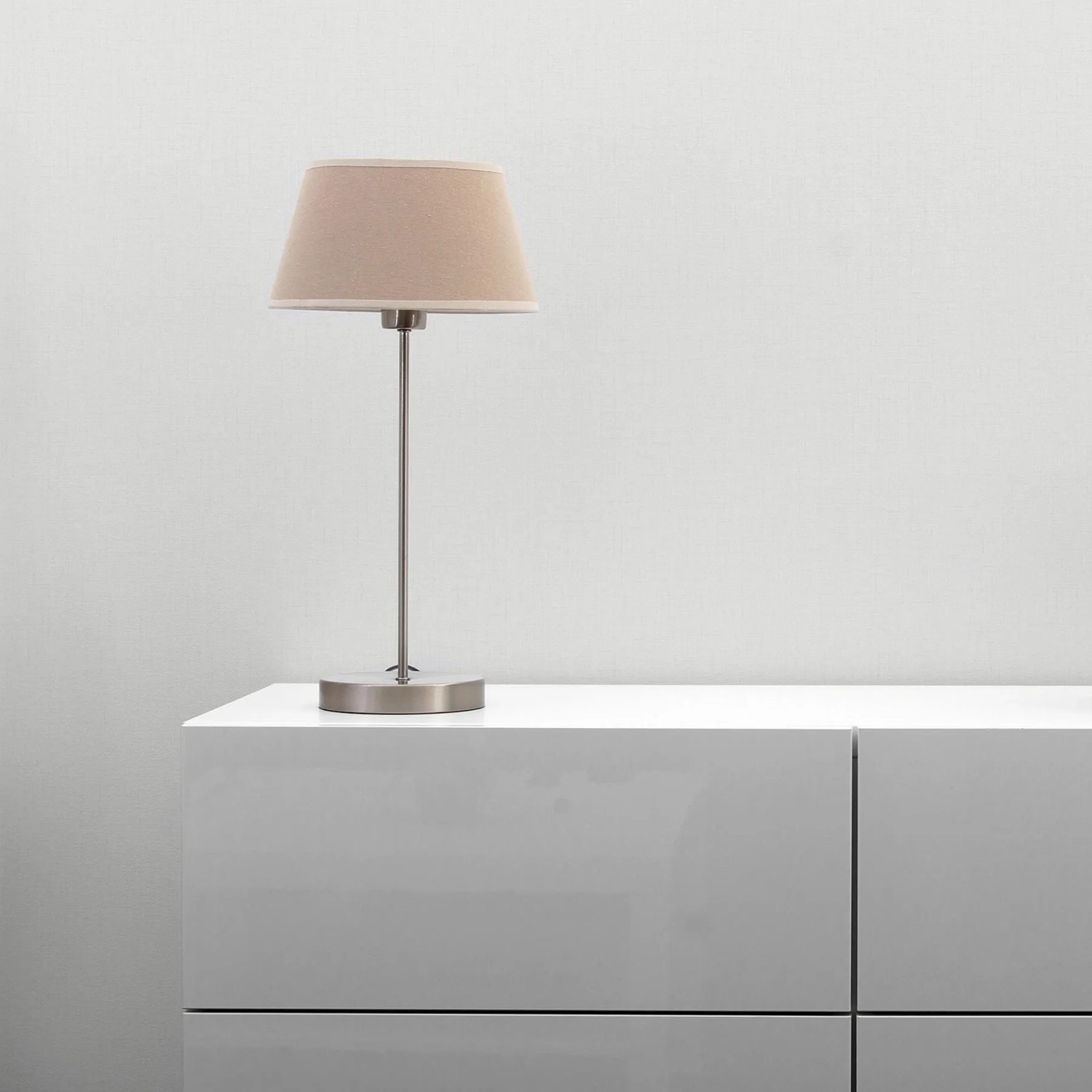 Weiße Tadessi Uni Vliestapete mit feiner Struktur an einer Wand, daneben ein moderner Schrank und eine Lampe.