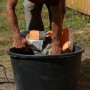 Mann schüttet Quick-Mix Ruck-Zuck Beton in einen Eimer. Schnellbeton für Montage und Fixierung.