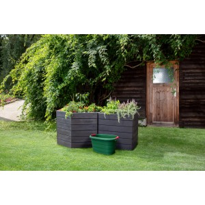 Grüner Garantia Universal-Behälter Toni Oval (46 l) vor bepflanzten Hochbeeten im Garten.