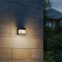 Schwarze Philips Solar-Außenwandleuchte Diara mit warmweißem Licht an Hauswand.