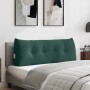 Dunkelgrünes Samt-Rückenkissen mit Knöpfen auf einem Bett. Ideal als Kopfstütze mit praktischer Seitentasche.