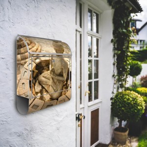 Silberner Banjado Briefkasten mit Motiv eines sitzenden Buddha und Zeitungsfach, an weißer Hauswand.