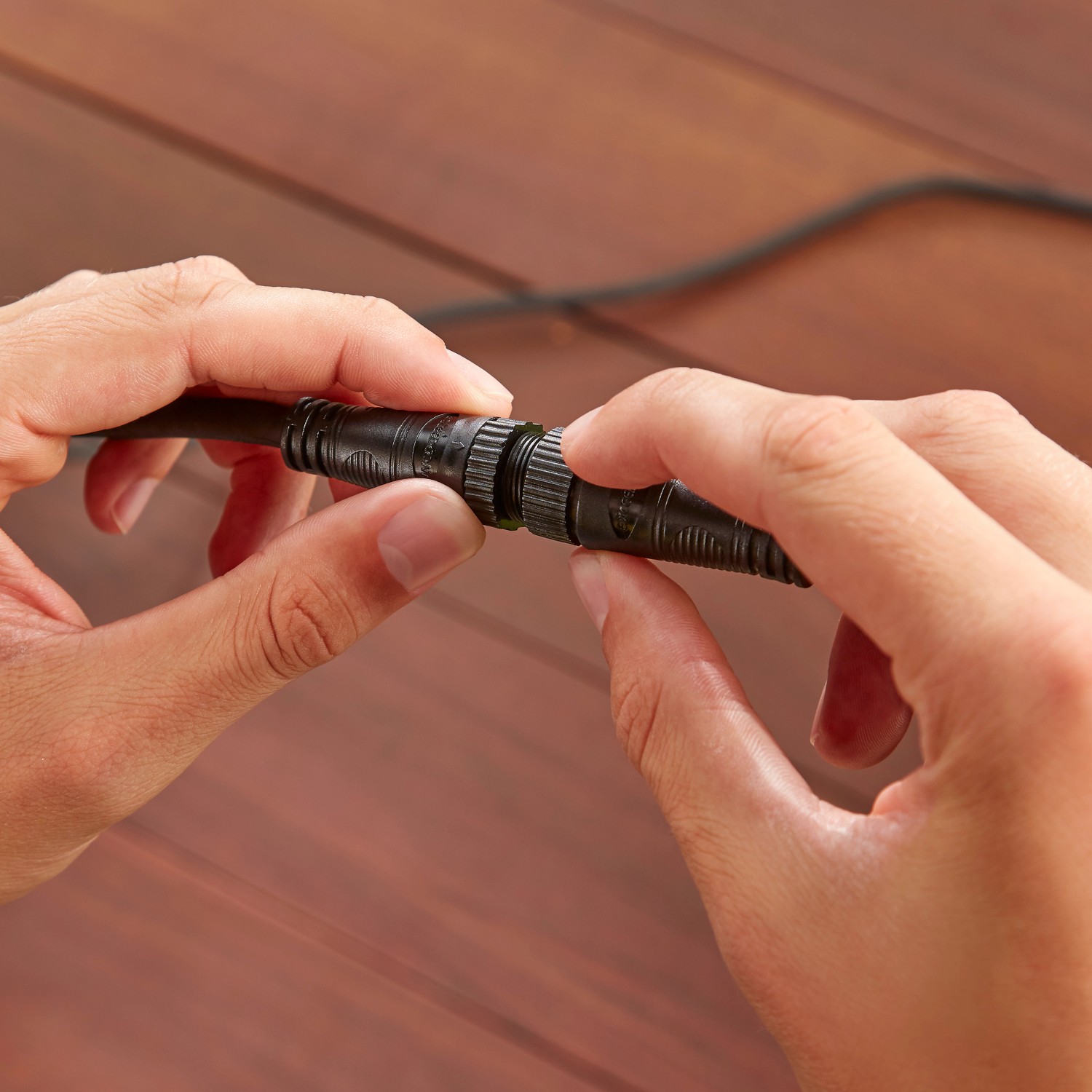 Detailaufnahme: Hände verbinden Philips Hue Outdoor-Netzteil (40W, 3,5m) für Niedervolt-Leuchten.