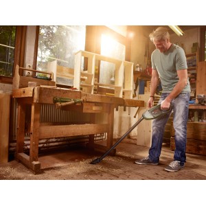 Mann nutzt Bosch Akku-Staubsauger EasyVac 12 mit Zubehör-Set in Werkstatt zum Reinigen von Holzboden.
