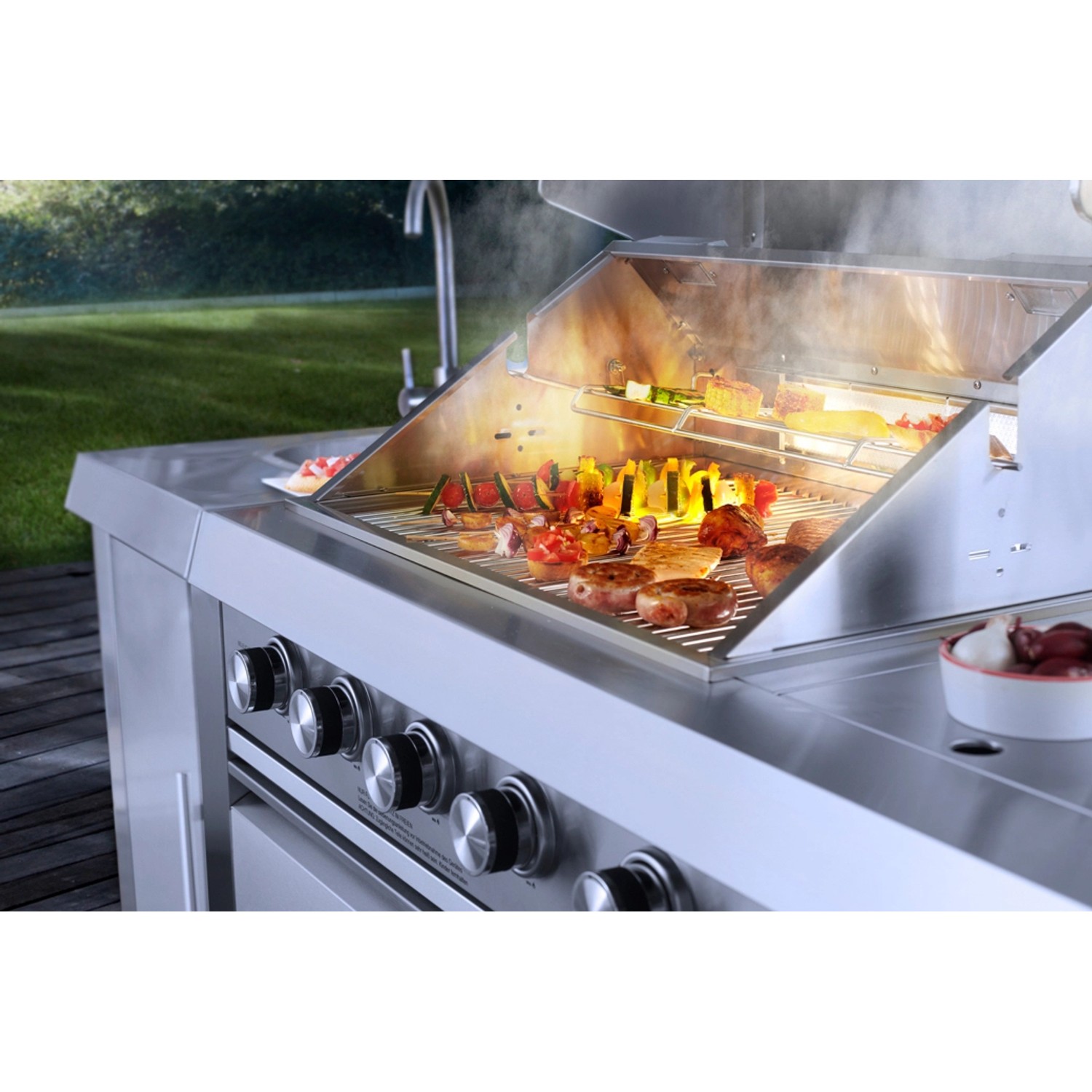 Buschbeck Outdoorküche Oxford mit Grillgut und Gemüse auf dem Grillrost.