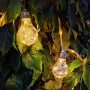 Warmweiße LED Solar-Lichterkette mit Glühbirnen im Hanfseil, dekorativ im grünen Laub für den Außenbereich.