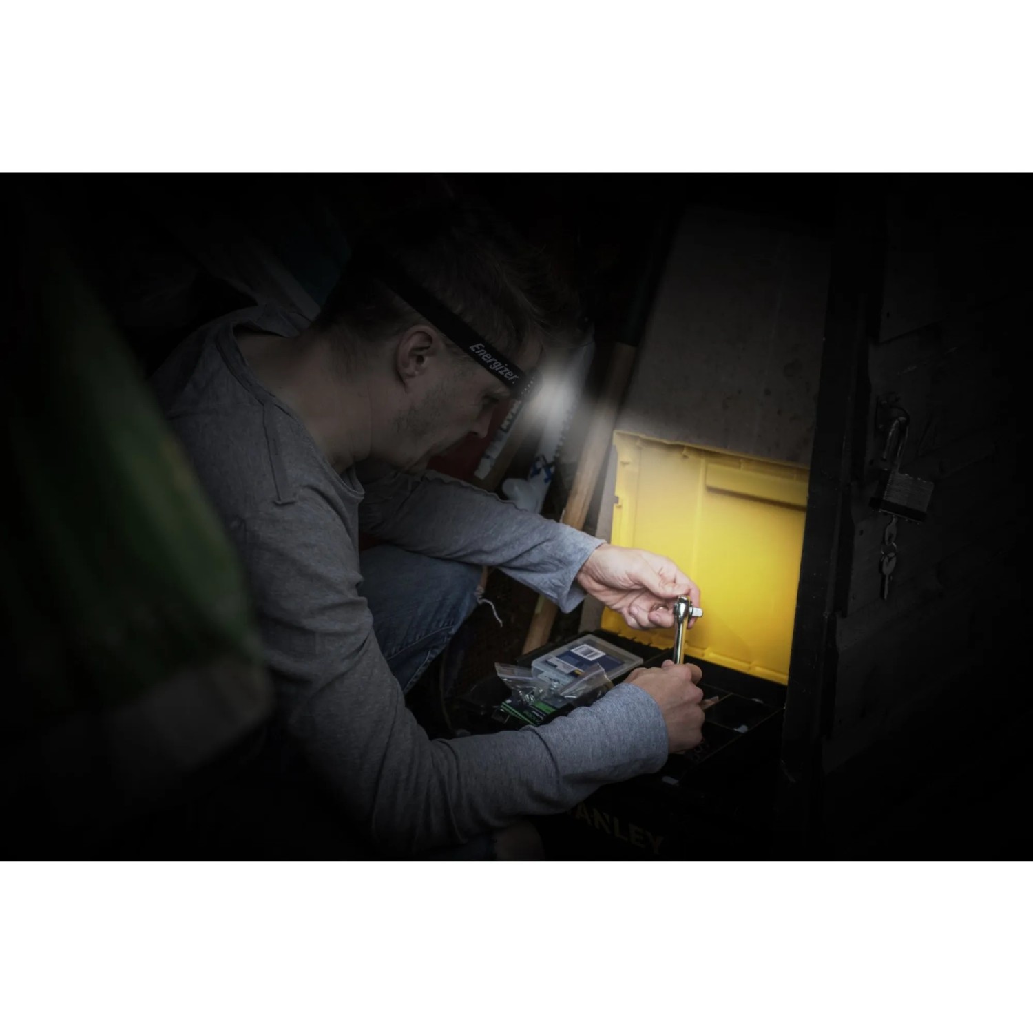 Mann arbeitet mit Energizer Kopflampe Universal + Headlamp. Taschenlampe leuchtet.