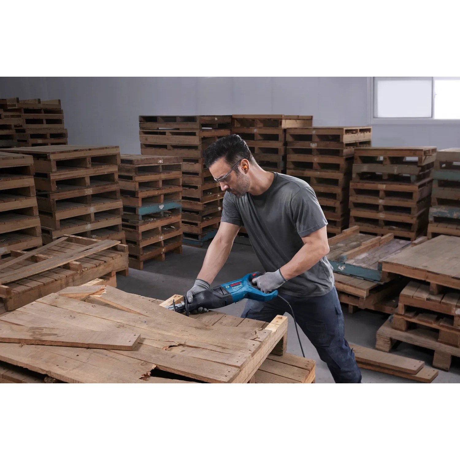 Mann sägt Holz mit Bosch Professional Säbelsäge GSA 12-30. Stichsäge im Einsatz.