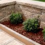 Kann Bruchsteinmauer Endelement Jura-Nuanciert, Ansicht einer Gartenmauer mit Pflanzen.