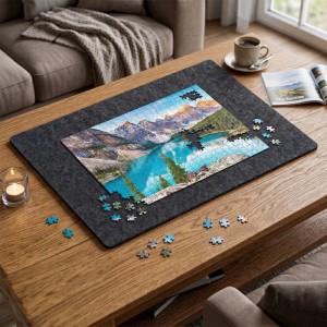 Graues faltbares Filz Puzzlebrett mit rutschfester Oberfläche auf Holztisch. Ein Bergsee-Puzzle ist darauf in Arbeit.