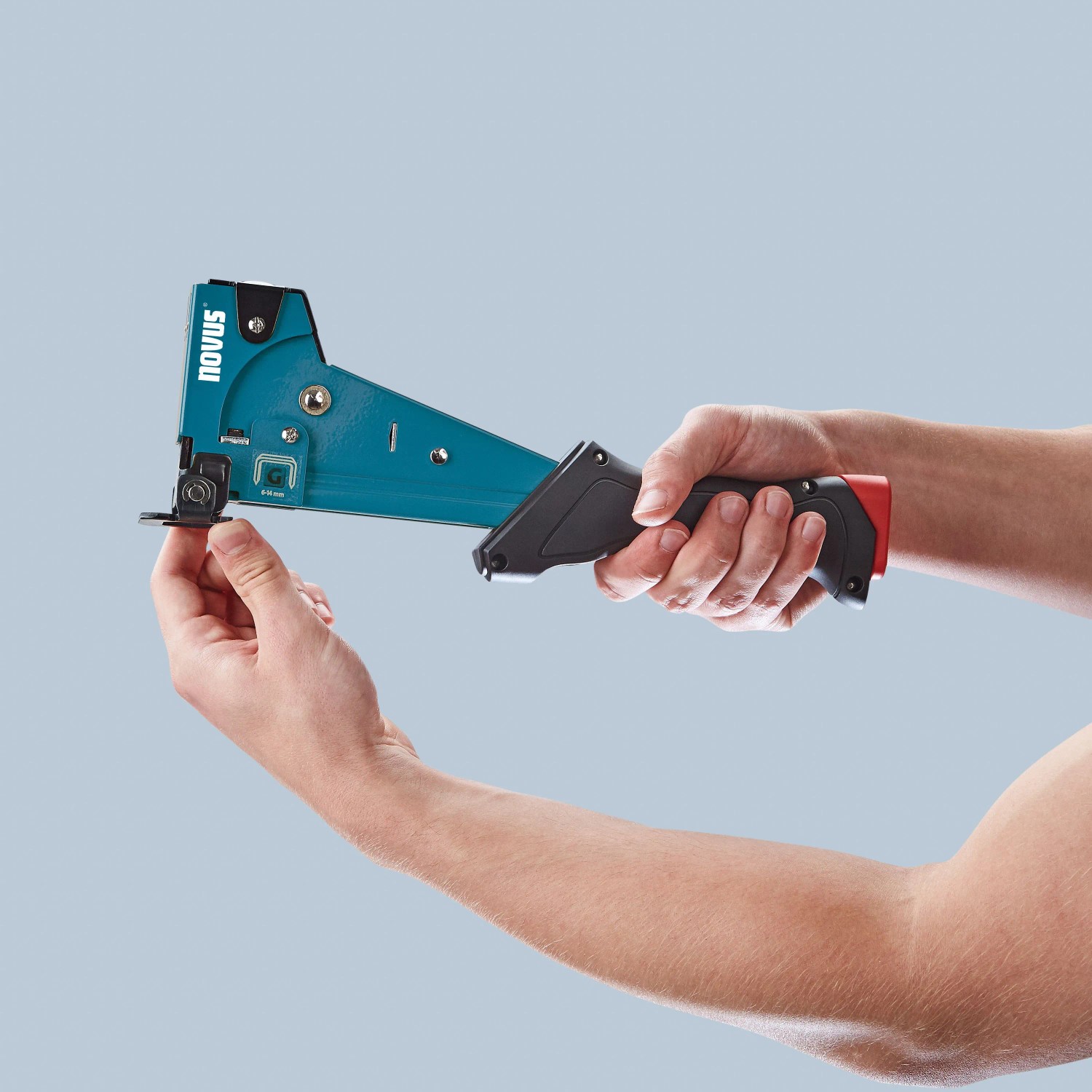Novus Hammertacker J-055 in Aktion: Handhabung des blauen Metall Tackers mit schwarzem Griff.