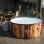 Runder LAY-Z-SPA Helsinki AirJet Whirlpool in Holzoptik mit Pumpe auf einer Terrasse.