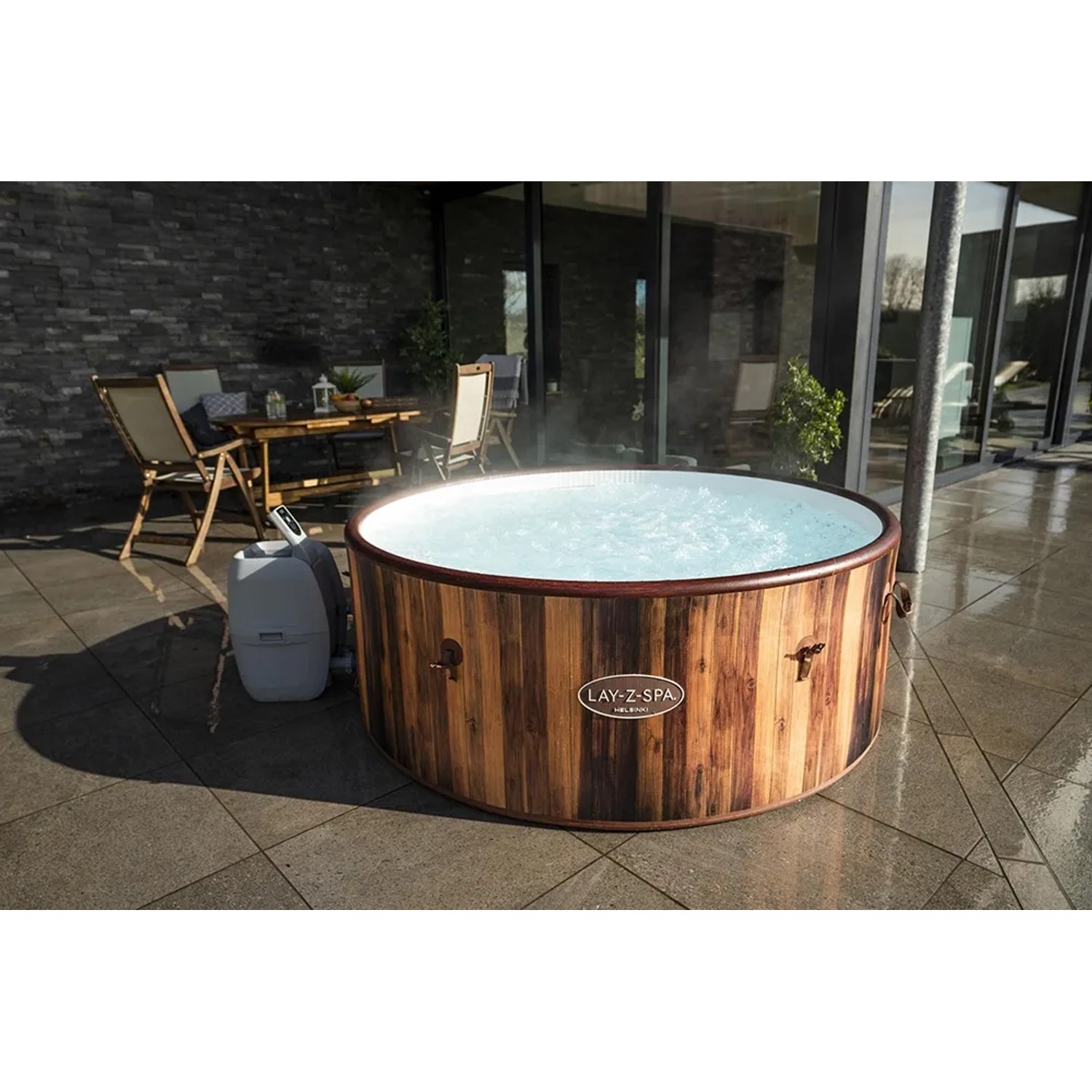Runder LAY-Z-SPA Helsinki AirJet Whirlpool in Holzoptik mit Pumpe auf einer Terrasse.