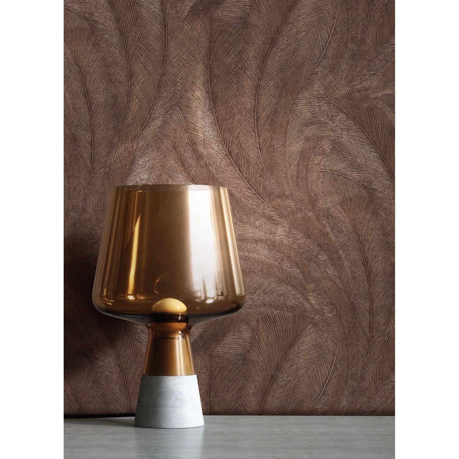 Strukturierte Vliestapete Savina mit bronzefarbenen Palmenblättern, Naturmotiv. Moderne Lampe im Vordergrund.