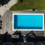 Draufsicht: Rechteckiger Steinbach Styropor Pool mit Holzdeck und blauer Poolabdeckung.