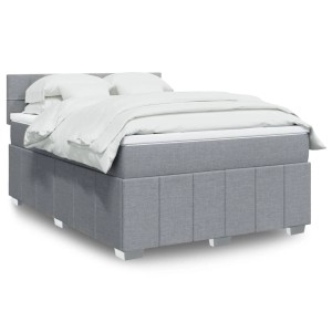 Hellgraues Boxspringbett 140x190 cm aus Stoff mit Kopfteil, Matratze und weißer Bettwäsche.