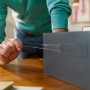 Anwendung von Tesa Universal-Klebeband Doppelseitig mit Nano-Power auf einer grauen Oberfläche.