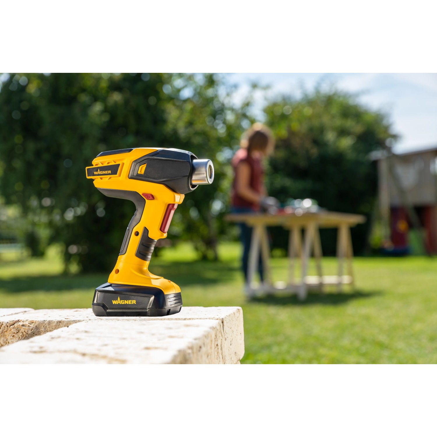 Gelbe Wagner Furno 550 18V Akku-Heißluftpistole im Garten, kabellos für DIY-Projekte.