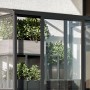 Schwarzes Aluminium Mini-Gewächshaus mit Glaswänden und grünen Pflanzen auf Regalen. Ideal für Balkon & Terrasse.