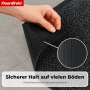 Anthrazitfarbene Floordirekt Schmutzfangmatte mit melierter Oberfläche. Hand zeigt rutschfeste TPE-Rückseite auf Fliesenboden.