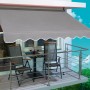Silbergraue Fallarmmarkise 2,5x1,5m am Balkon mit Tisch und Stühlen.