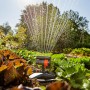 Gardena Viereckregner Aqua Zoom Compact bewässert Gemüsebeet. Regner mit Wasserstrahlen im Einsatz.