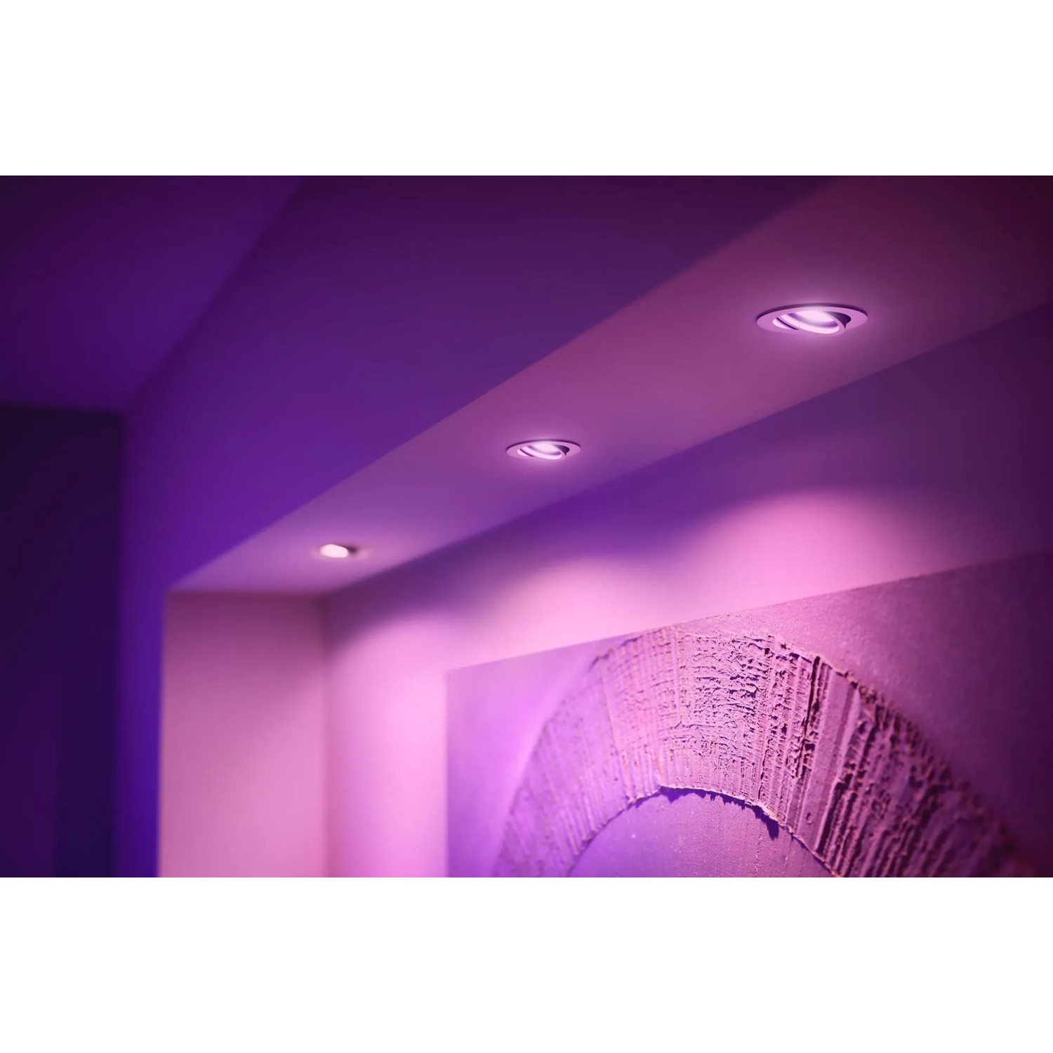 Philips Hue Centura Einbauspots, 3er-Pack, Weiß, mit farbigem Licht in einem Raum.