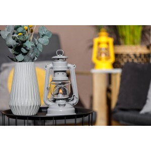Feuerhand Sturmlaterne Baby Special Grau auf Tisch mit Deko. Stromlose Lichtquelle für Garten & Camping.