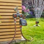 Gardena Bewässerungscomputer Select am Wasserhahn mit Regner im Garten.