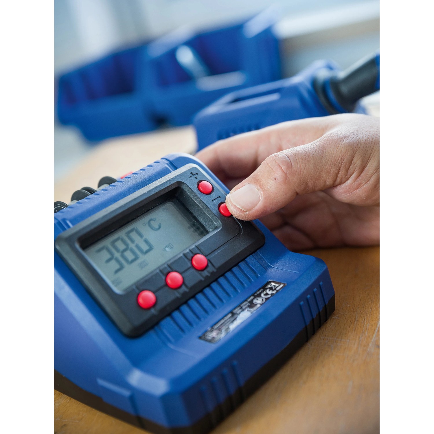 Blaue LUX-TOOLS Lötstation LST-60 mit digitaler Temperaturanzeige und Hand am Bedienknopf.