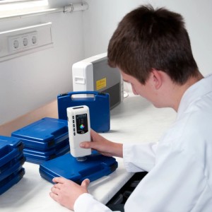 PCE Instruments Colorimeter CSM 1 bei Farbmessung auf blauem Koffer, Prüfwerkzeug für hohe Messgenauigkeit.