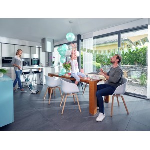 Familie feiert Geburtstag, während Mutter mit dem Leifheit Akku-Saugwischer den Boden reinigt.