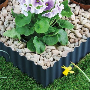 Bellissa Rasenkante Welle, anthrazit, 500x14 cm, umrandet Blumenbeet mit Steinen.