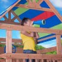 Kind im Spielturm Northbrook mit Fernglas unter buntem Dach. Holzspielturm mit Spielzeug.