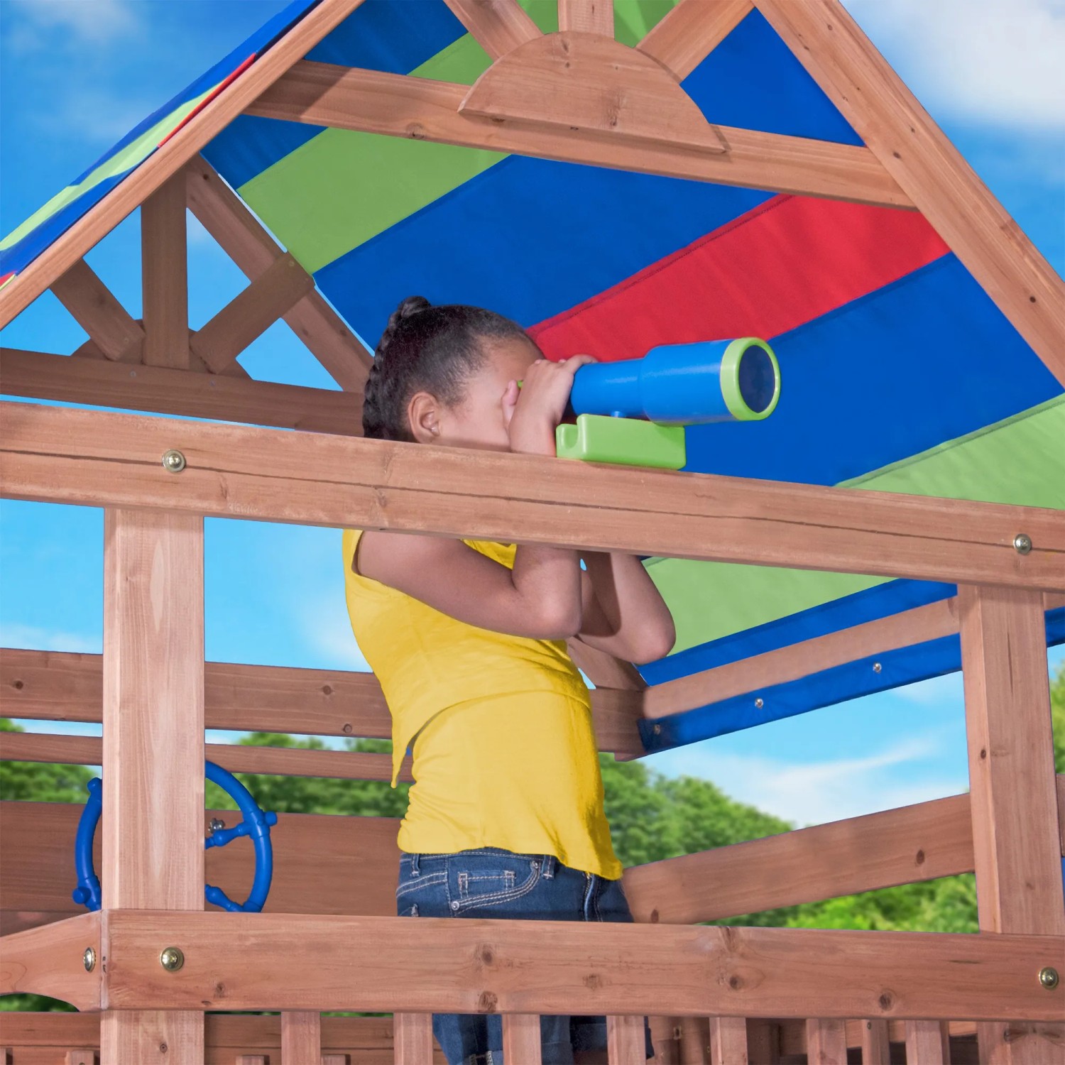 Kind im Spielturm Northbrook mit Fernglas unter buntem Dach. Holzspielturm mit Spielzeug.