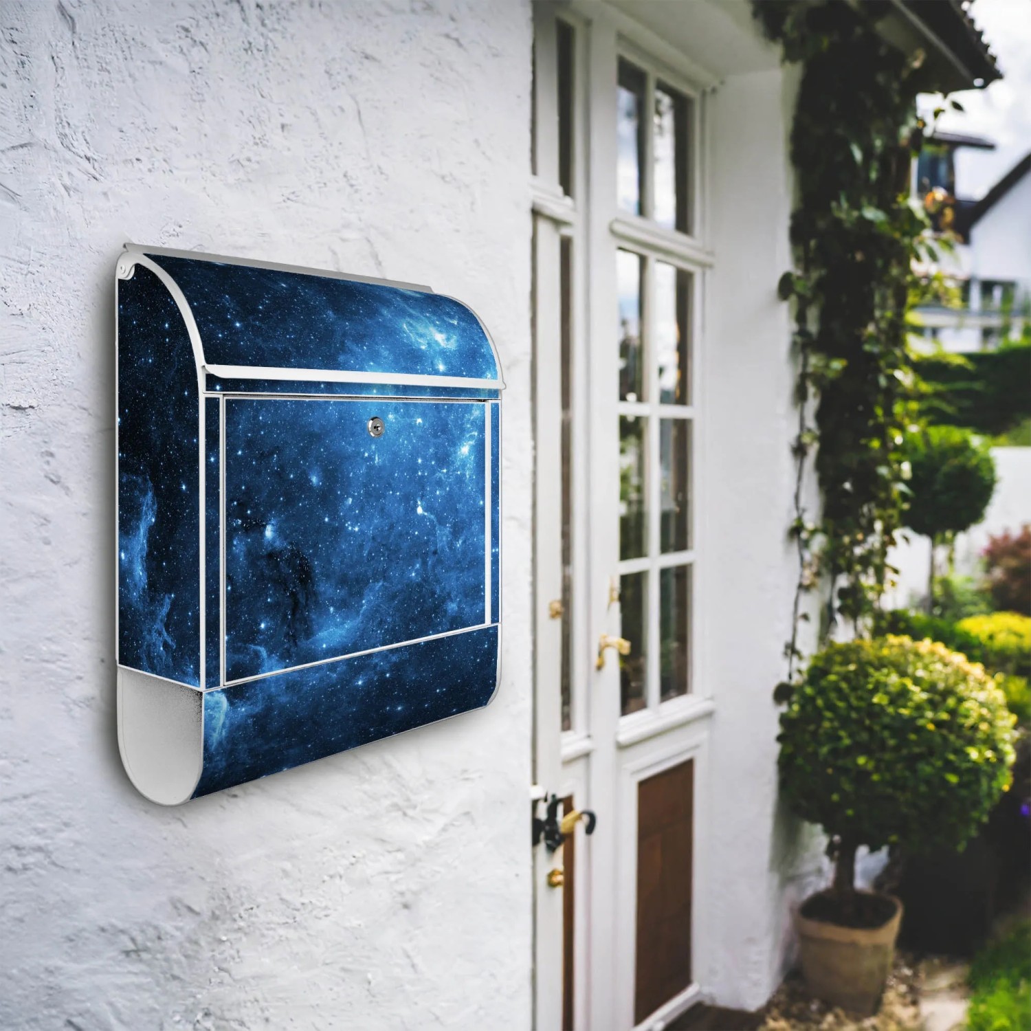 Weißer Banjado Design Briefkasten mit Universum Motiv und Zeitungsfach an Hauswand.