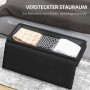 Schwarze Polsterbank mit offenem Stauraum, gefüllt mit gefalteten Decken. Praktischer Hocker mit Aufbewahrung.