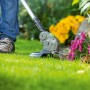 LUX Akku-Rasentrimmer A-RT-20/26 im Einsatz beim Trimmen von Rasen an Blumenbeet.