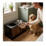 Erhöhte Relaxdays Hundefutterstation Industrial-Schwarz aus MDF mit 2 Edelstahlnäpfen und Schrankfach. Hund wird gefüttert.