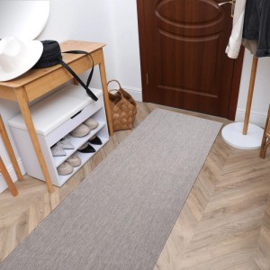 Grauer, flach gewebter Sisal-Läufer im Flur auf Holzparkett. Schmaler Teppich für Eingangsbereiche.