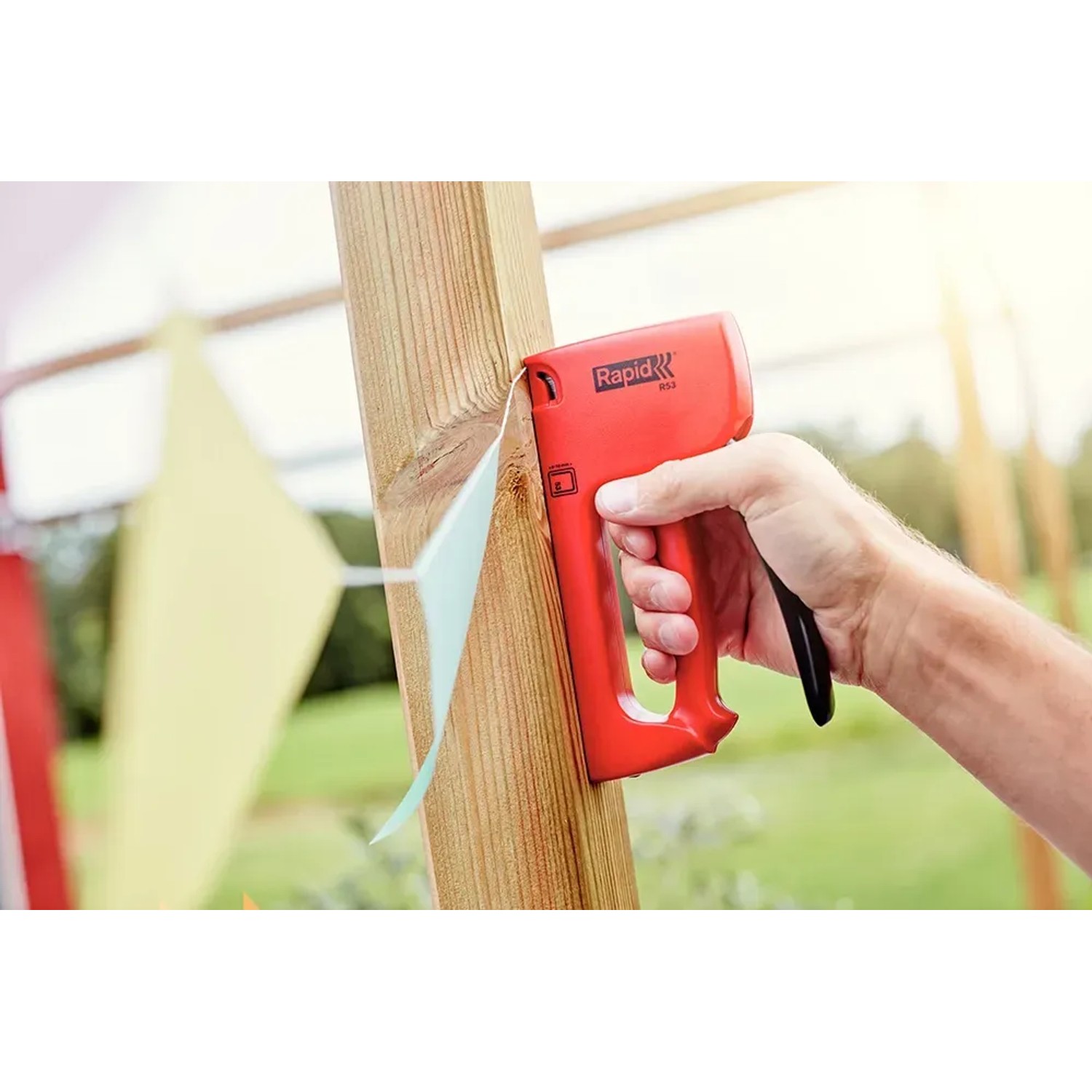 Rapid Handtacker R53 in Aktion: Befestigen einer Girlande an einem Holzpfosten.